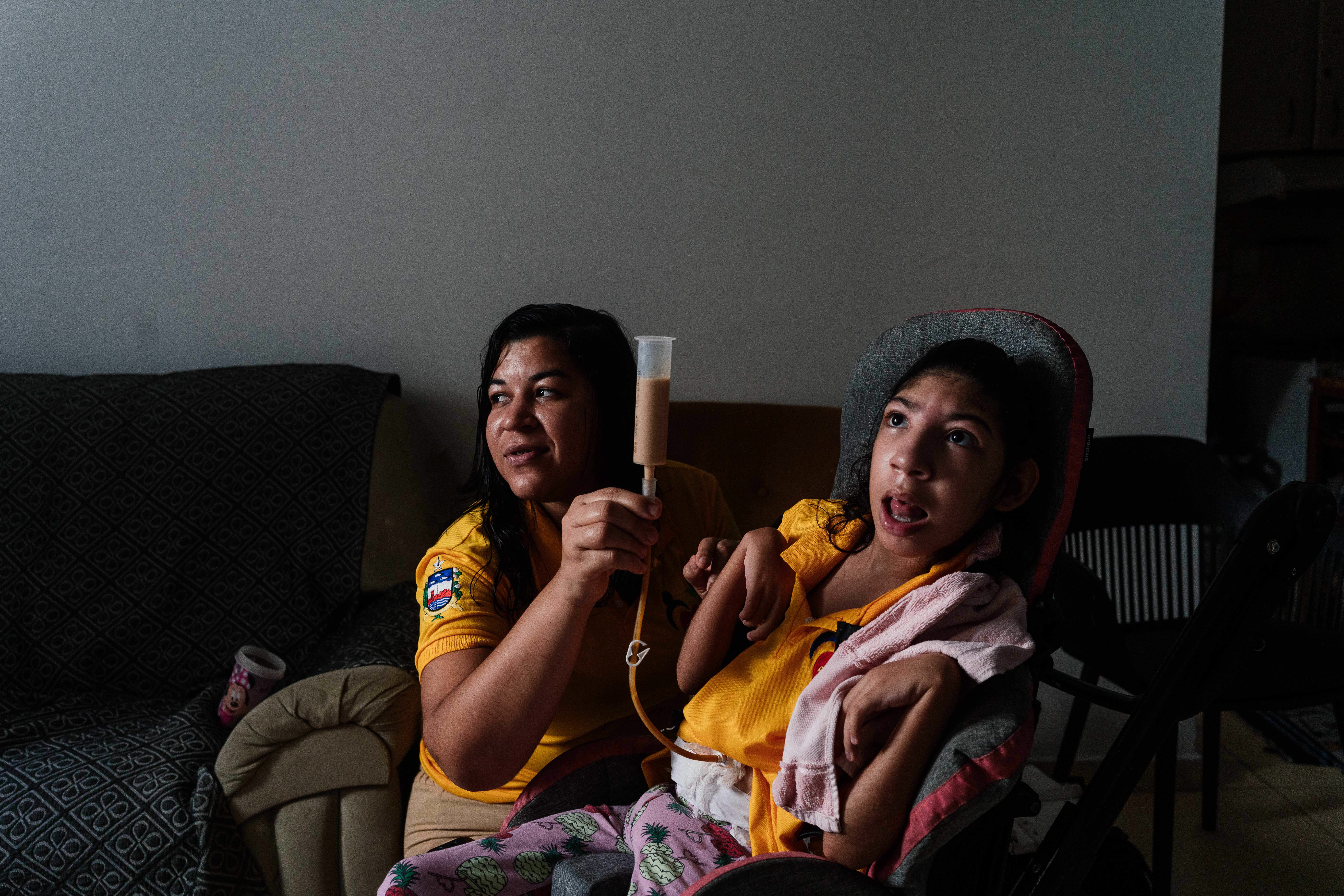Ruty Pereira sits with her daughter, Tamara, in their apartment in Maceió, in eastern Brazil. Tamara, whose development was impacted in utero by the Zika virus, eats through a feeding tube.